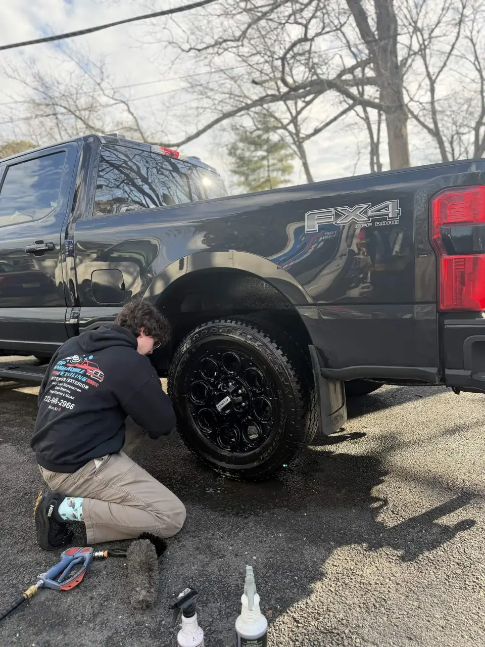 Top Wash detailer cleaning the wheels of a black Ford Super Duty FX4
