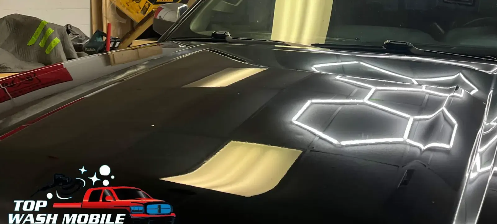 Black hood after Top Wash paint correction, reflecting hexagon shop lights