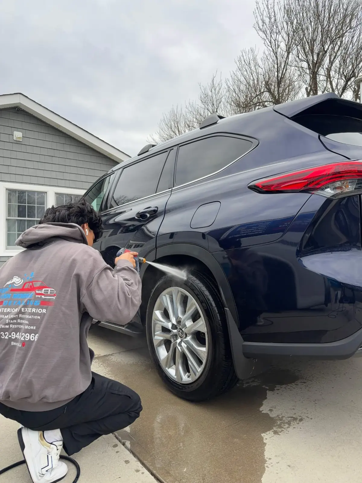 Sebastian washing the wheel well of a Toyota Highlander